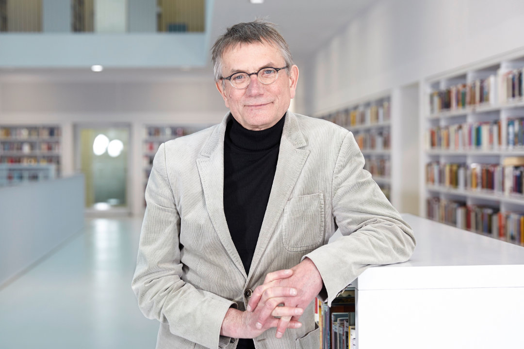 Portrait von Jörg Armbruster, aufgenommen in einer Bibliothek von Christina Kratzenberg
