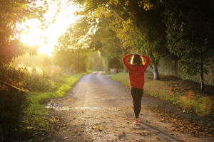 Frau in Sportsachen auf einer Strasse bei Sonnenaufgang