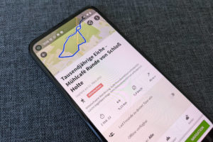 Ein Smartphone zeigt die geöffnete App "Komoot", zu sehen ist eine Karte mit iener eingezeichneten Route.